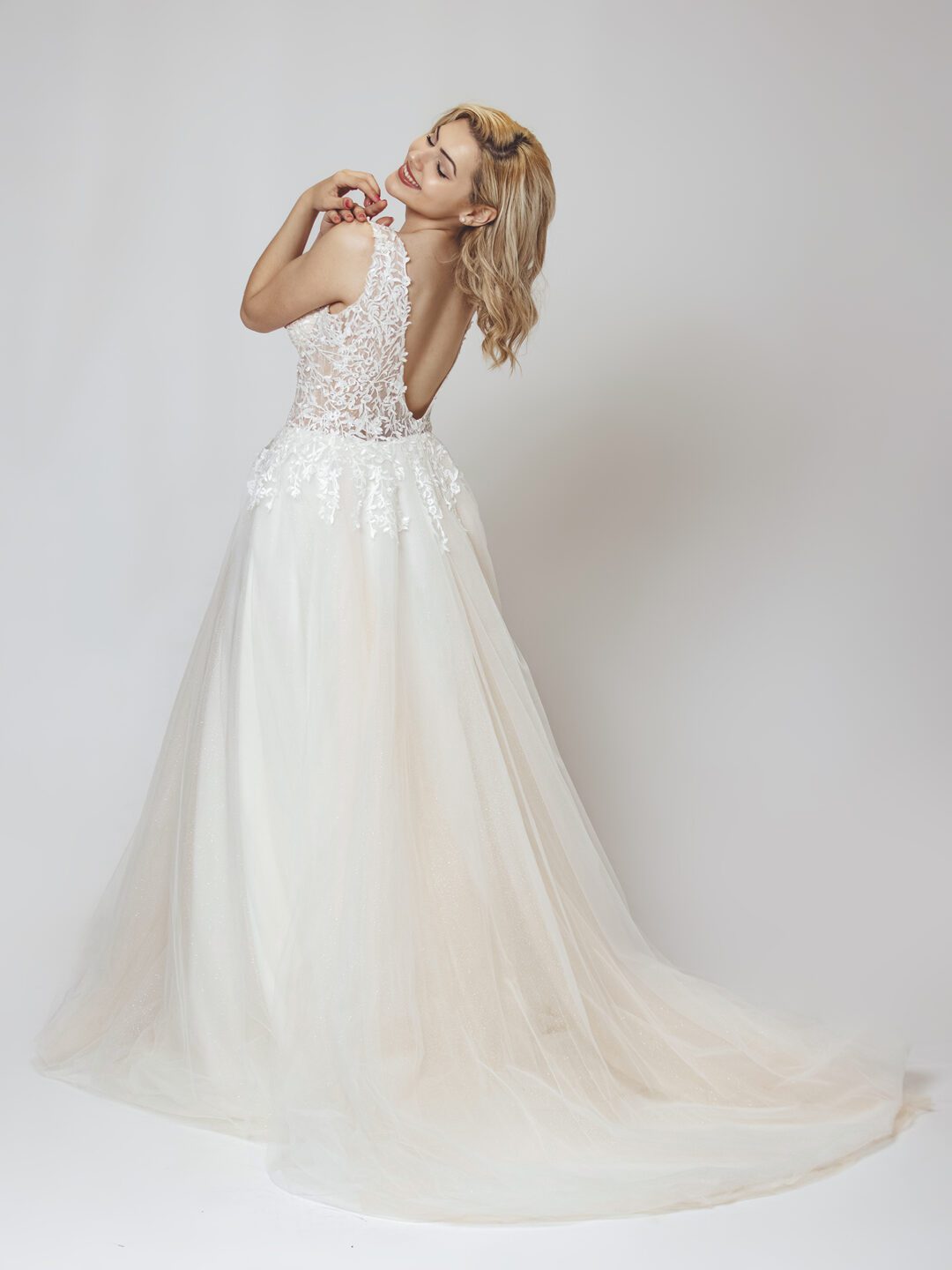 Εντυπωσιακό νυφικό με διαφάνεια στο μπούστο και κεντημένο με ανάγλυφη γαλλική δαντέλα. Φούστα σε άλφα γραμμή, από γαλλικό τούλι σε λευκό με νερά στο χρώμα της πούδρας. Ανοιχτή πλάτη σε βαθύ V. 